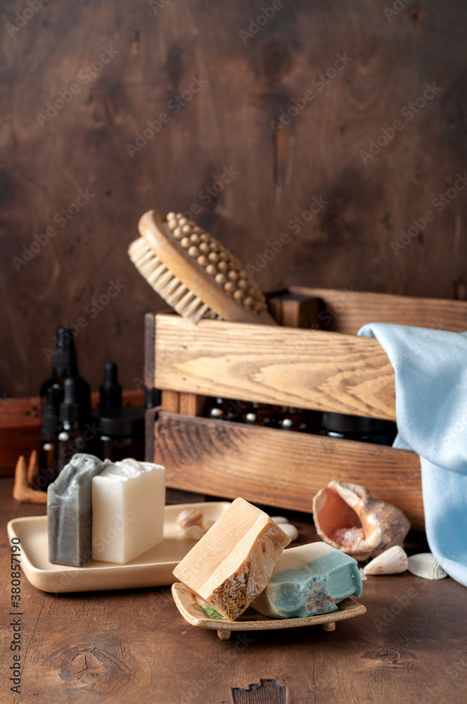Natural handmade soap bar in ceramic soap dish with spa accessories on wooden table