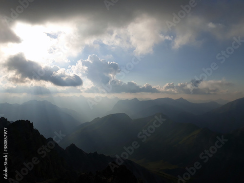 Berggipfel, Silhouette mit dunkler Wolkenstimmung und Sonnenstrahlen.