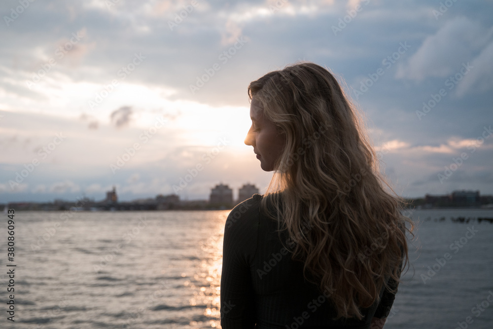 Female model standing with the sun setting in front of her Female model standing with the sun setting in front of her
