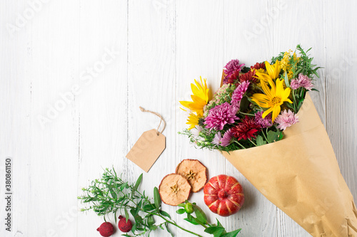 Autumn bouquet of yellow and pink flowers on white wooden background.
