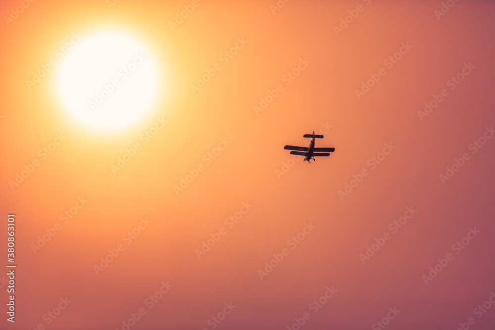 Small airplane flying in the sunset with sun in haze Small airplane flying in the sunset with sun in haze