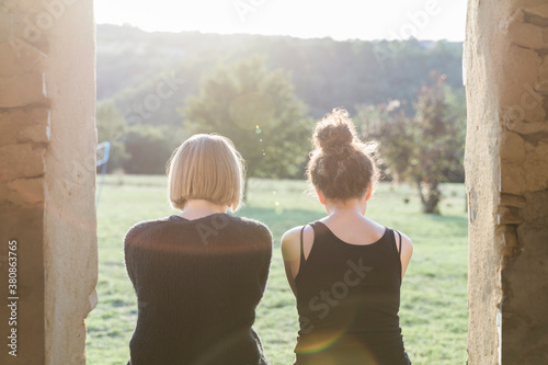 Two female friends sitting on stairs at sunset photo