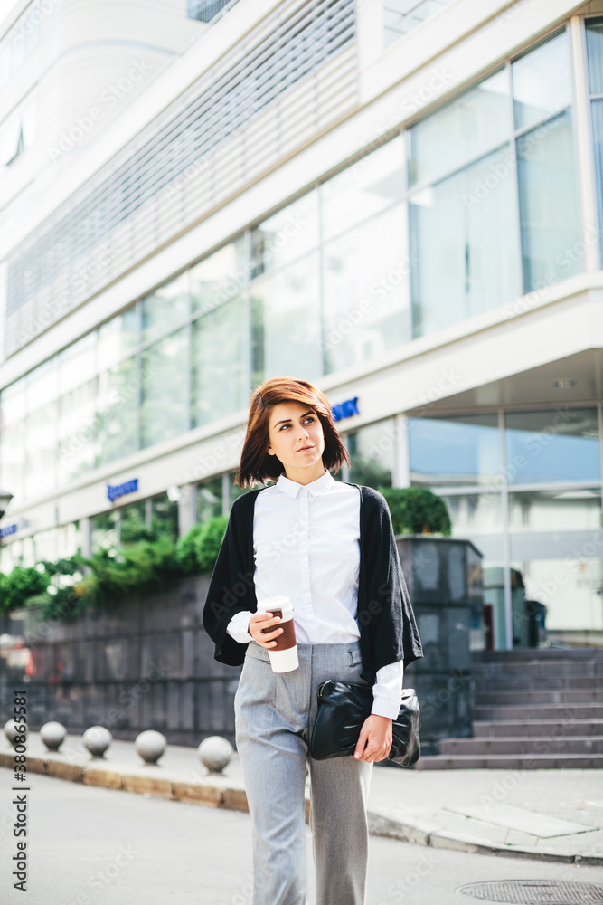 Young business woman walking on the street with coffe in her hands Young business woman walking on the street with coffe in her hands