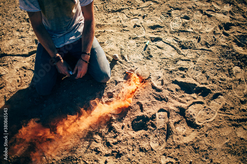 A man kneeling in the dirt next to a trail of fire photo