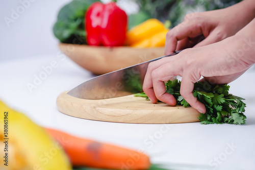 Woman hands cutting coriander in the kitchen. Chef cooking vegan food. Chef preparing vegetables in kitchen