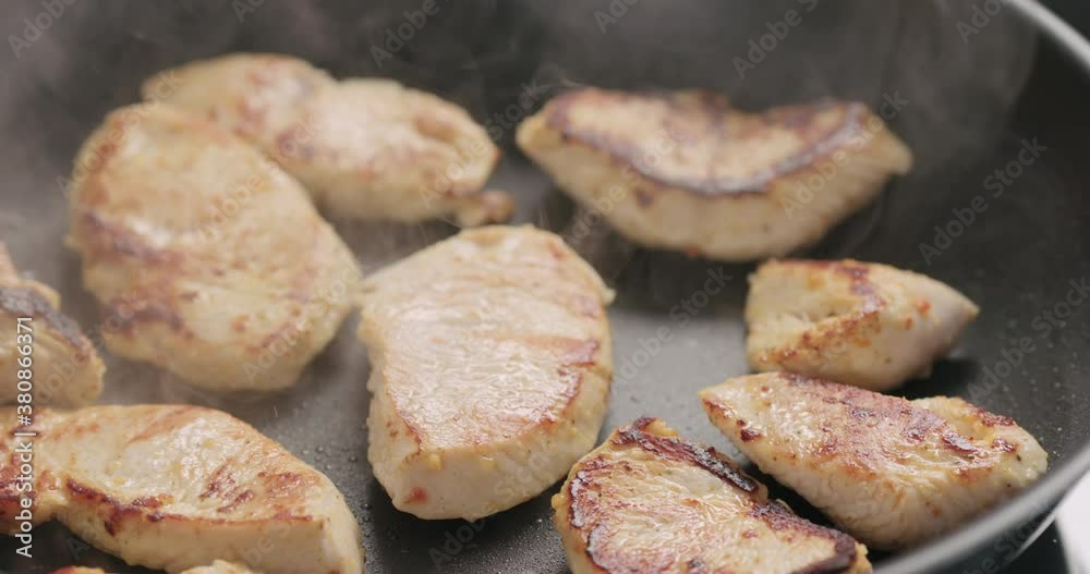 Slow motion handheld shot of turkey fillet pieces frying on nonstick pan Slow motion handheld shot of turkey fillet pieces frying on nonstick pan