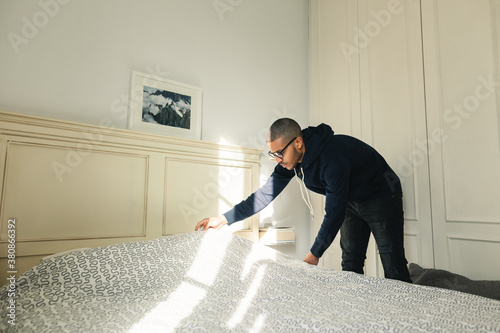 Latin man making bed at home. photo