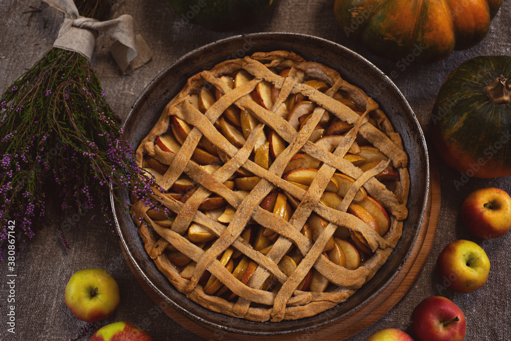 Preparation, Thanksgiving Day celebration. View from above. Baked apple pie in a baking sheet. Close-up. In the background are pumpkins. Making a traditional apple pie. Preparation, Thanksgiving Day celebration. View from above. Baked apple pie in a baking sheet. Close-up. In the background are pumpkins. Making a traditional apple pie.