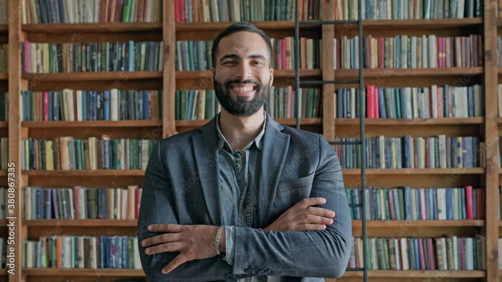 Guy Is Standing In The Library. Attractive Brunette With Beard From The Middle East. Guy Is Standing In The Library. Attractive Brunette With Beard From The Middle East.