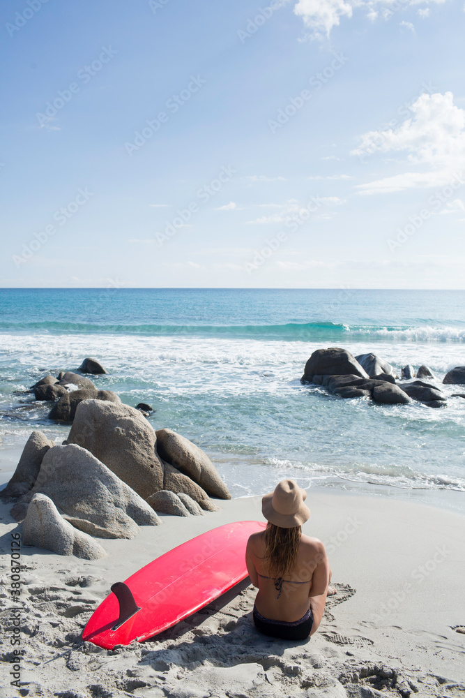 Girl sits on the beach with her surfboard Girl sits on the beach with her surfboard
