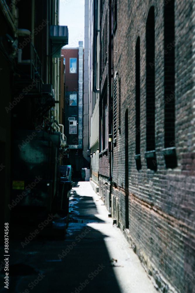 Narrow, dead end alley half lit by sunlight Narrow, dead end alley half lit by sunlight