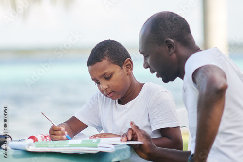 Father is teaching his home schooled son during a vacation