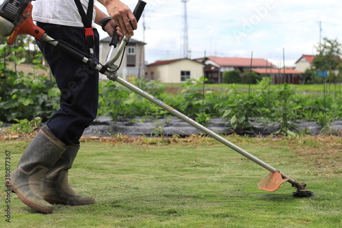 芝刈り機で庭の雑草を刈っている男性