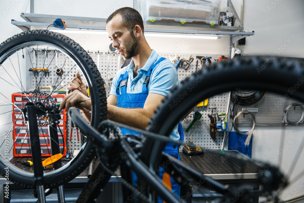 Obraz premium Bicycle repair in workshop, man setting up brake