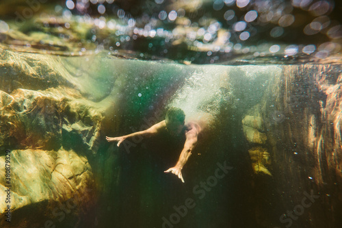 Man dives into rockpool water leaving a trail of bubbles photo