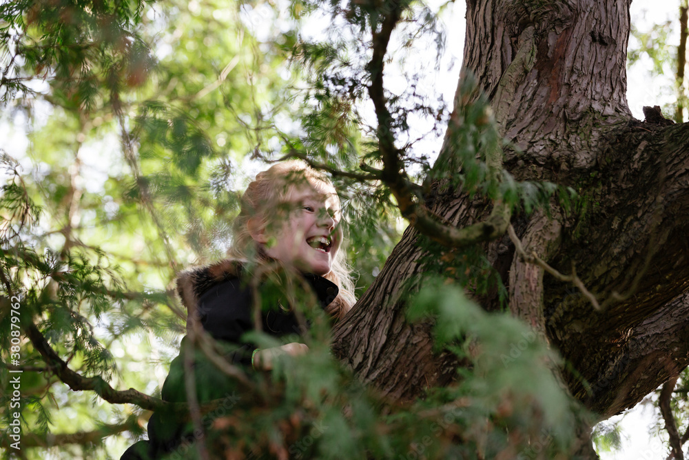 Child laughing as she climbs higher up a tree Child laughing as she climbs higher up a tree