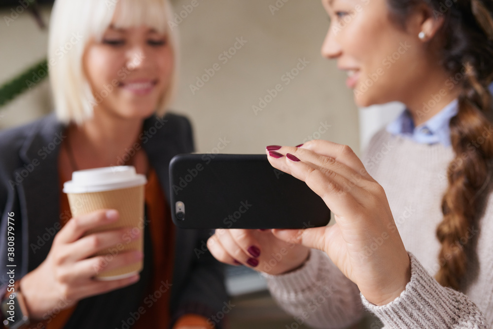 Stylish young women friends discuss social media on smart phone Stylish young women friends discuss social media on smart phone