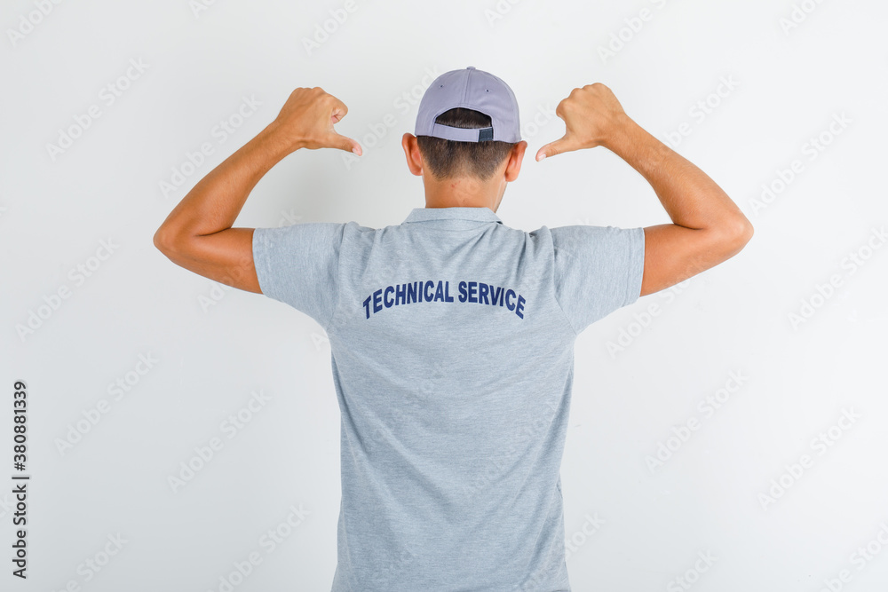 Technical service man showing text on uniform in grey t-shirt, cap , back view. Technical service man showing text on uniform in grey t-shirt, cap , back view.