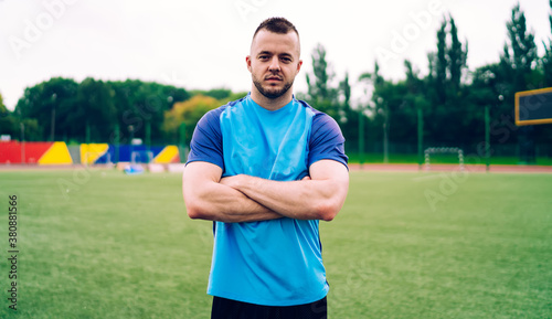 Male athlete standing on sports field with arms crossed