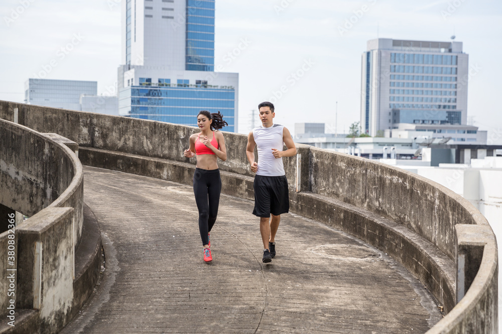 A handsome young couple jogging together in an urban environment A handsome young couple jogging together in an urban environment