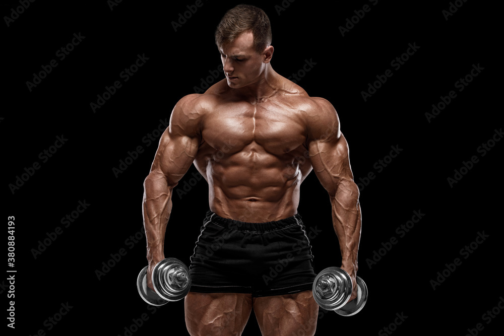 Muscular man with dumbbells isolated on black background. Strong male naked torso abs
