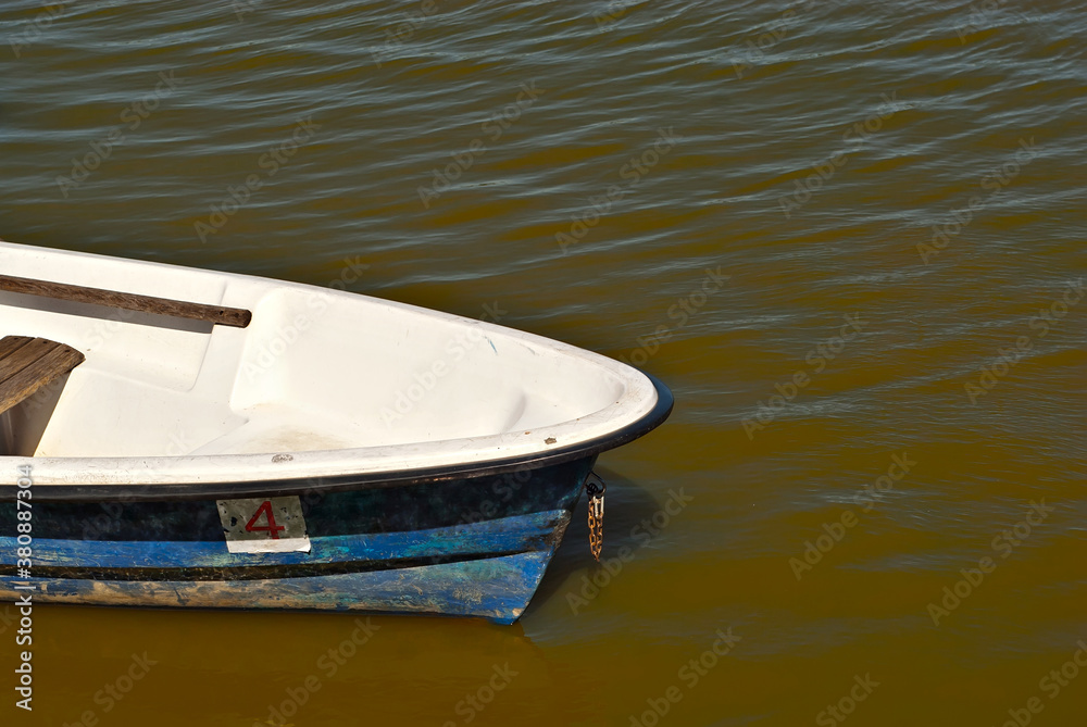 Old white boat on the lake near the pier.