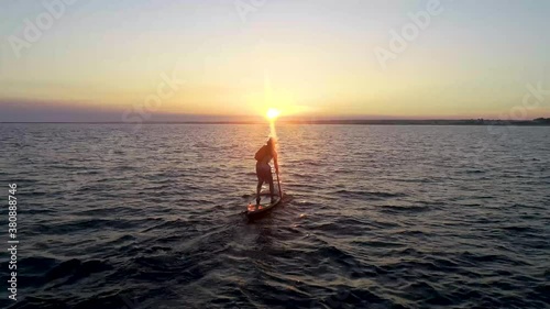 Paddleboarder chasing the sunset across a bay photo