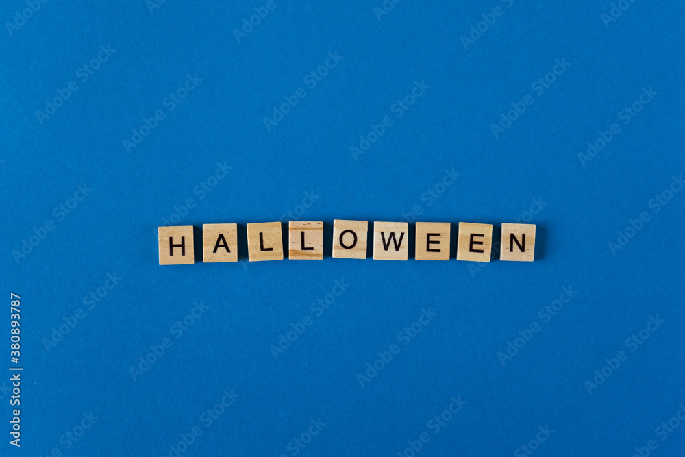 The word Helloween is lined with wooden letters on a blue background top view. Postcard in place for text. Flatlay. The words. Banner. The word Helloween is lined with wooden letters on a blue background top view. Postcard in place for text. Flatlay. The words. Banner.