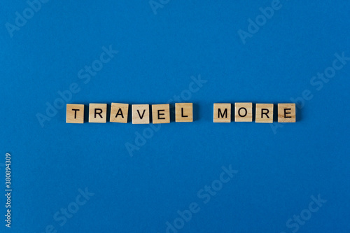 The words travel moor is lined with wooden letters on a blue background top view. Postcard in place for text. Flatlay. The words. Banner.