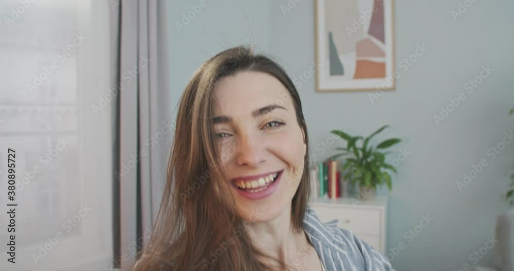 POV of beautiful Caucasian happy girl smiling and talking on video call in living room at home. Close up portrait of cheerful pretty woman having video chat indoors in good mood. Conversation concept POV of beautiful Caucasian happy girl smiling and talking on video call in living room at home. Close up portrait of cheerful pretty woman having video chat indoors in good mood. Conversation concept