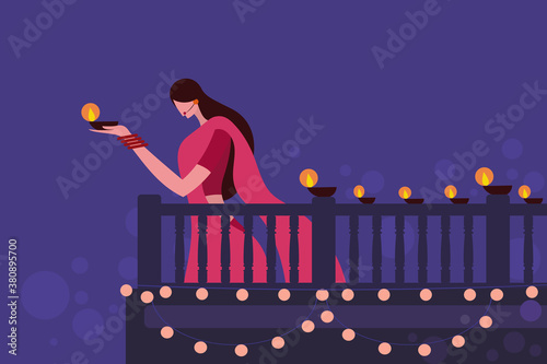 A woman wearing traditional dress holding Diwali festival lamps in her hand