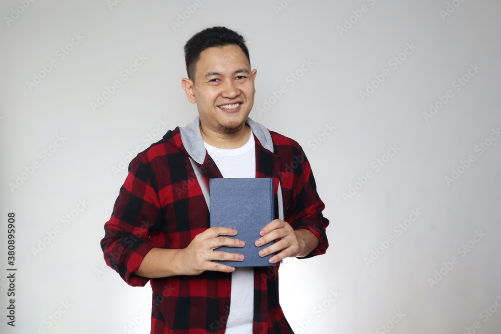 Young Asian man reading a book, smiling expression Young Asian man reading a book, smiling expression