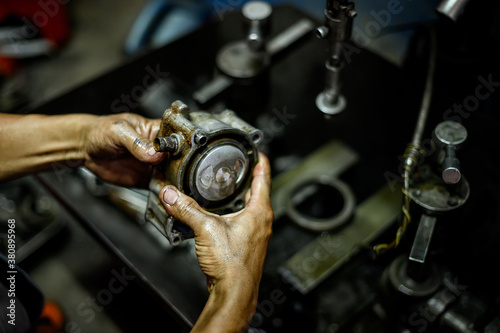 Holding a motorcycle piston with blurred machine background. Motorcycle engine repair.