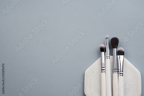 Professional makeup brushes on a white stand on a gray background