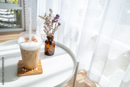 Iced coffee on table in cafe with sunlight through the curtains.