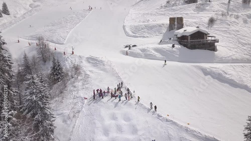 Aerial drone shot over people skiing down the steep white snowy slopes of Verbier, Switzerland. photo