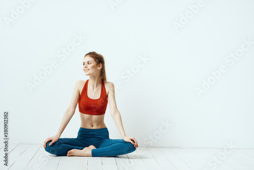 athletic woman in pose on the floor exercise gymnastics performance light background