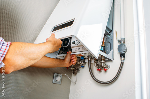 Plumber attaches Trying To Fix the Problem with the Residential Heating Equipment. Repair of a gas boiler photo