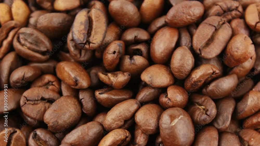 Roasted grains of aromatic coffee rotate on a plate. Close-up of the rotation of coffee beans. Roasted grains of aromatic coffee rotate on a plate. Close-up of the rotation of coffee beans.