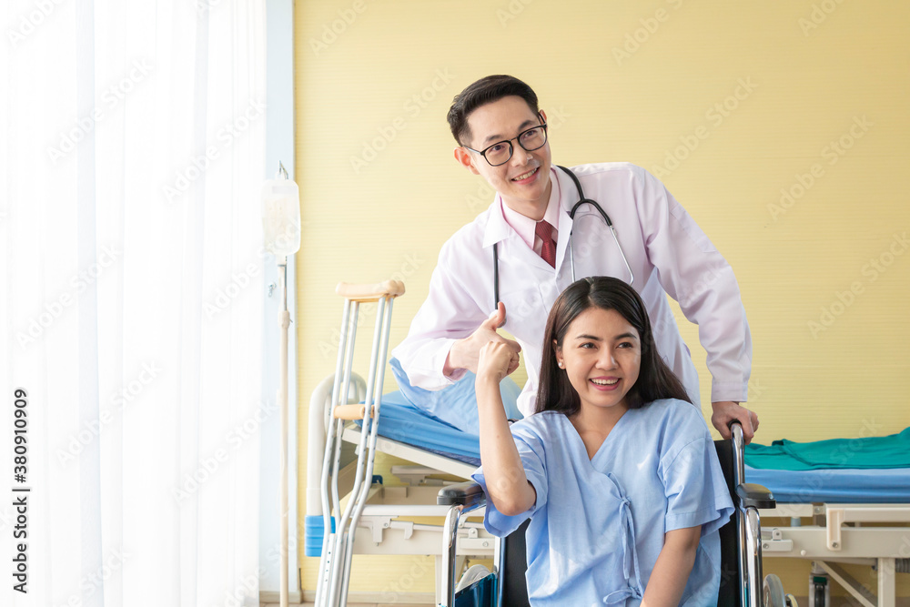 Young Doctor talking to woman in wheelchair after an operation. Smiling doctor looking at a female patient on a wheelchair in hospital. Photo of positive doctor and patient on wheelchair. Young Doctor talking to woman in wheelchair after an operation. Smiling doctor looking at a female patient on a wheelchair in hospital. Photo of positive doctor and patient on wheelchair.