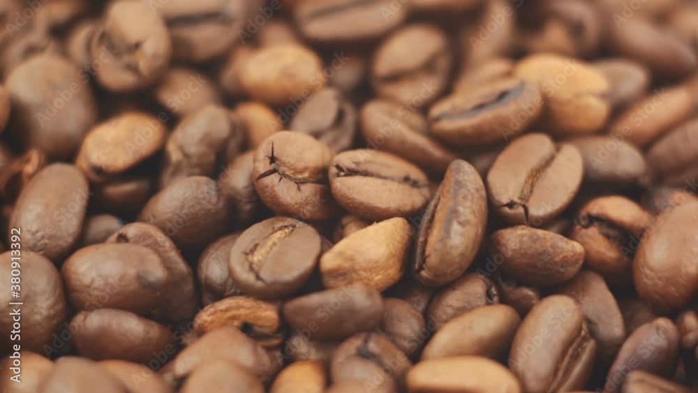 Close-up of the rotation of coffee beans. Roasted grains of aromatic coffee rotate on a plate. Close-up of the rotation of coffee beans. Roasted grains of aromatic coffee rotate on a plate.