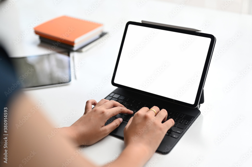 Businesswoman working on her project while typing on tablet computer with white screen in modern office. Businesswoman working on her project while typing on tablet computer with white screen in modern office.