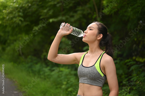 Beautiful women resting and drinking water after doing exercises in park.