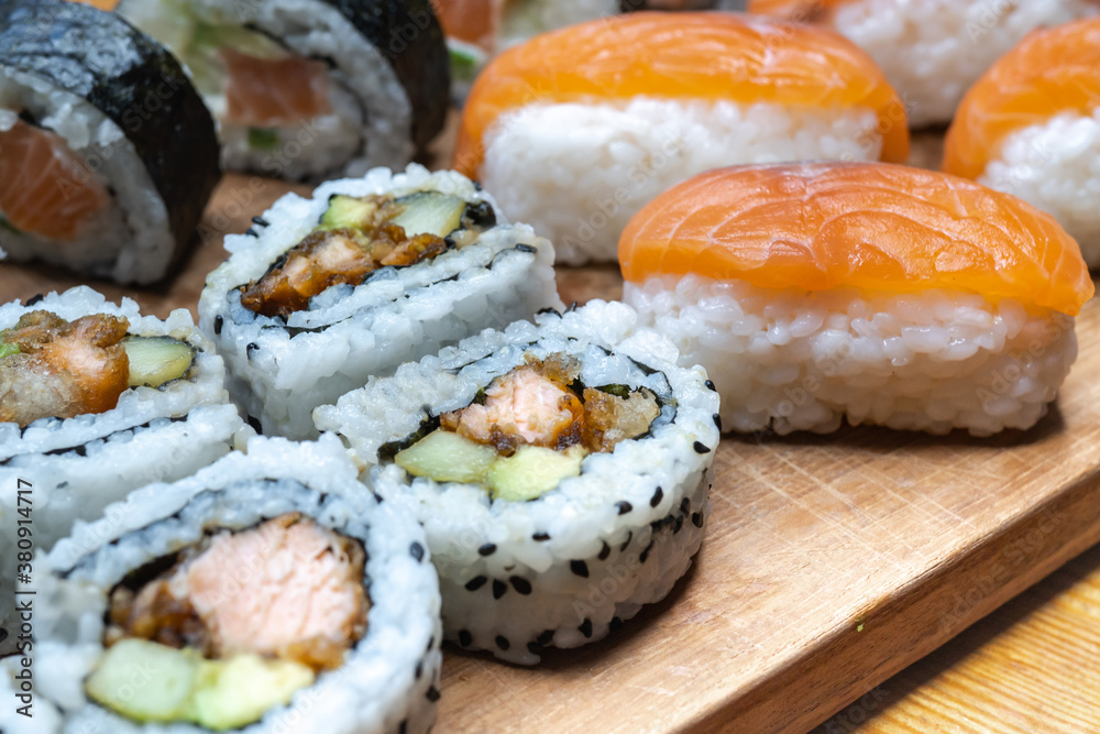 One set of Japanese salmon sushi rolls served on a wooden board. One set of Japanese salmon sushi rolls served on a wooden board.
