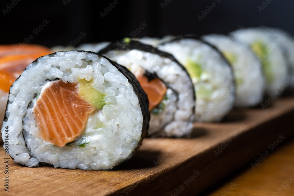 One set of Japanese salmon sushi rolls served on a wooden board. One set of Japanese salmon sushi rolls served on a wooden board.
