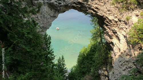 Arch Rock on Mackinac Island, Michigan. Docked boat with swimmers in turquoise Great Lakes waters visible through the arch. photo