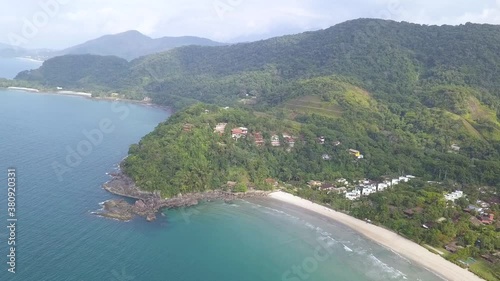 Wide Aerial shot slowing flying forward of Barra do sahy beach the south alantic ofcean and accompanying tropicla tourism town in Brazil photo