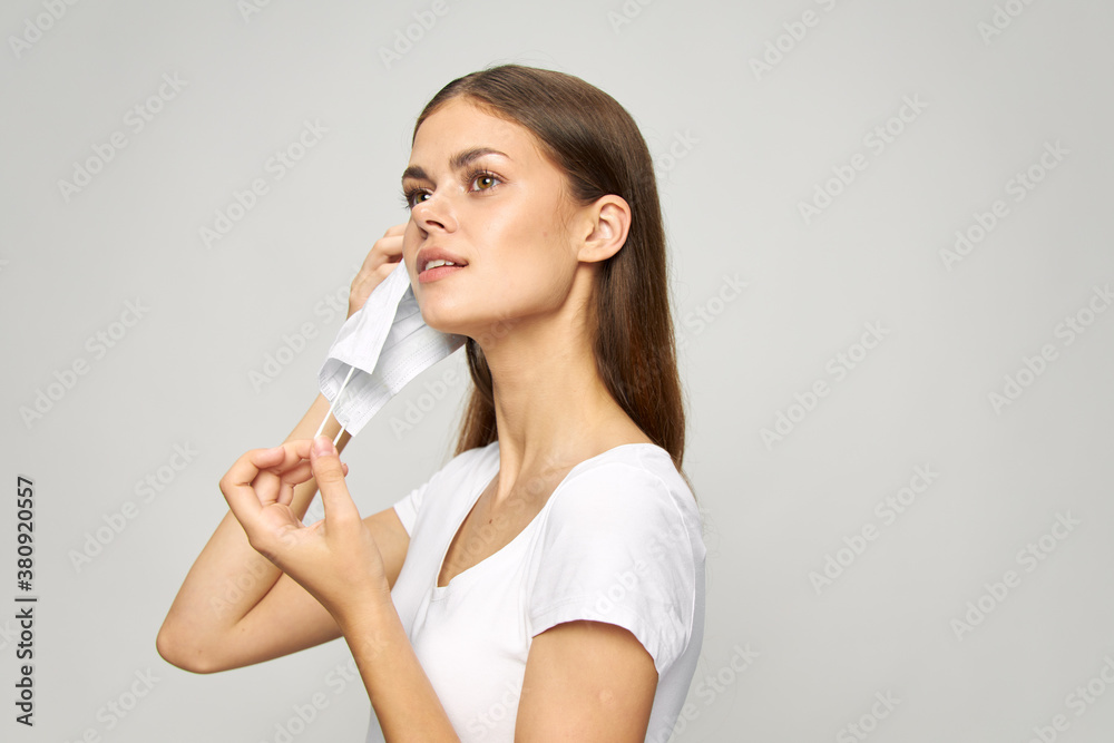 Portrait of a woman puts a medical mask on his face white t-shirt Portrait of a woman puts a medical mask on his face white t-shirt
