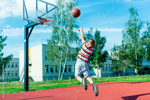 Fotografia Attractive east european caucasian little basketball player jumps to throw the ball into the hoop