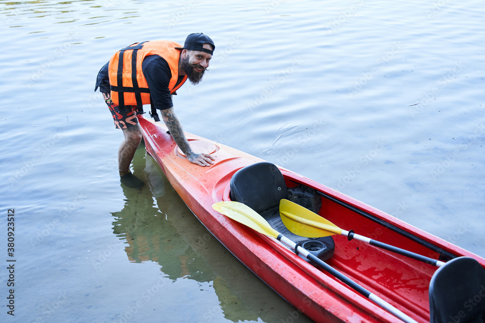 Obraz premium Man in safe jacket pulling canoe